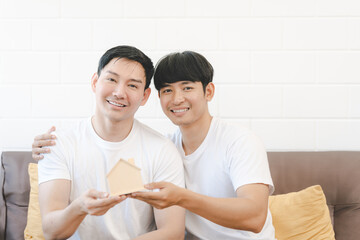 Asian Gay Couple Buying New Dream House Or Property with house model. Concept for marriage, loan, finance, insurance, mortgage, real estate and property.