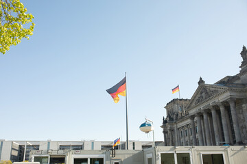 Fototapeta na wymiar The Bundestag building, Parliament of the Federal Republic of Germany, with German flag flying outside.