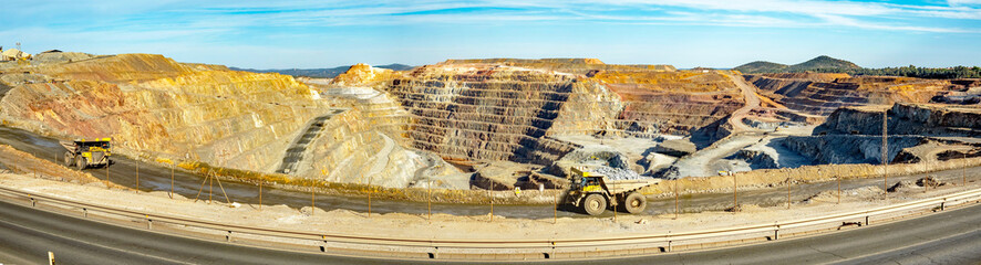 Dump trucks driving along Cerro colorado, the largest active open pit mine in Europa producing...
