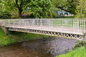 White iron bridge over a river in a park