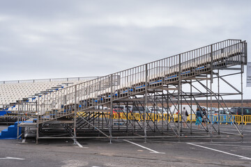 bleachers installed on the esplanade of a public parking lot for an open-air concert. Blue and...