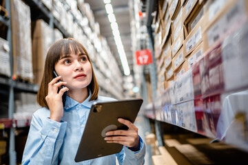 Warehouse Worker using smartphone and digital tablets to check the stock inventory in large warehouses, a Smart warehouse management system, supply chain and logistic network technology concept