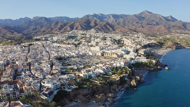 Aerial drone shot of Andalusian coastal town Nerja with seaside cliffs and mountains