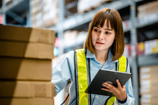 Women warehouse worker using digital tablets to check the stock inventory on shelves in large warehouses, a Smart warehouse management system, supply chain and logistic network technology concept