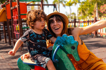 Mother having fun with her son in a playground on summer vacation