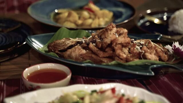 Delicous Thai cuisine dishes served in colorful plates on wooden table.