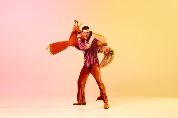 Emotional, artistic young couple, man and woman in stylish bright clothes dancing retro dance...