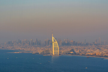 Dubai seaside skyline and Burj Al Arab luxury hotel aerial view and skyscrapers far away at sunset, United Arab Emirates. High quality photo