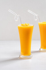 Fresh beautiful delicious mango juice smoothie in glass cup on gray table background.