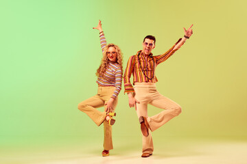 Expressive, talented young couple, man and woman in stylish vintage costumes dancing against...