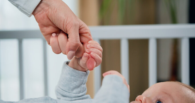 Close-up of hand of mother and infant at children room background. Concept of motherly love, new life and newborn baby
