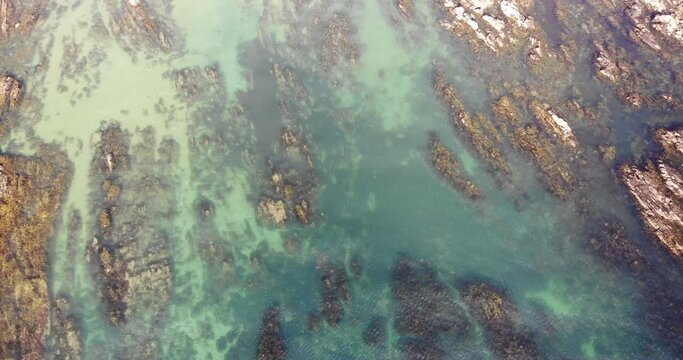 Aerial panning right shot over turquoise waters and beautiful rock formations