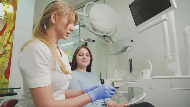 The dentist consults the patient and shows the woman Invisalign braces, transparent plastic removable aligners. Dentistry, dental clinic, orthodontics.