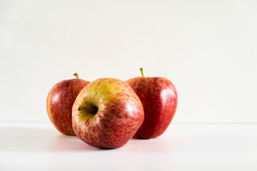 Three fresh red apples on a white background.