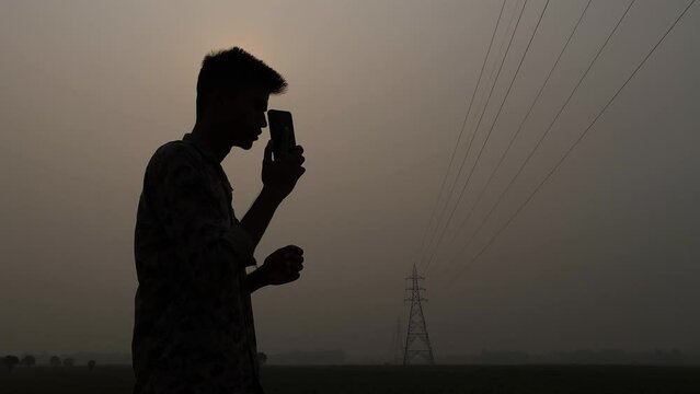 Asian man picking up his cellphone on rural area. Silhouette. Network communication concept
