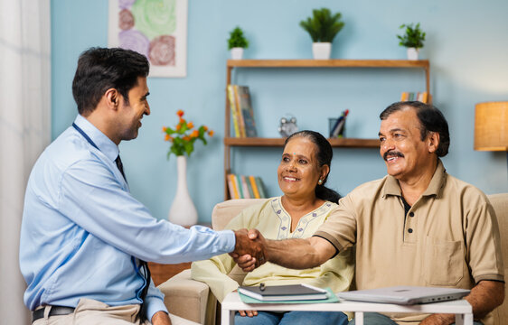 Indian banking officer greeting by hand shaking to senior couple at home - concept of financial advisor, expert consultation and professional occupation