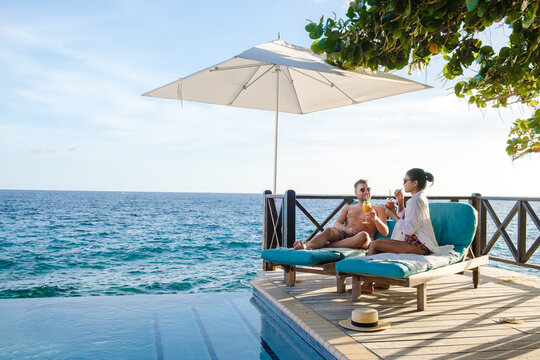 Curacao, couple man and woman mid age relaxing by the swimming pool during a vacation in the Caribbean