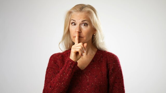 Secret Elderly Blonde Middle Age Woman 60s 50s Years Old Casual Sweater Saying Hush Be Quiet With Finger On Lips Shhh Gesture Isolated On Solid White Background Studio Portrait