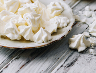 Meringue cookies in in a plate on wood