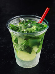 Mojito cocktail in a plastic glass with a tube