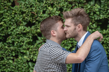 Fototapeta premium Happy couple gay holding hands looking to each other in the park. Lgbt lover man homosexual gay hug together.