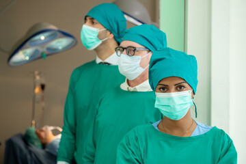 Fototapeta na wymiar Multidisciplinary teamwork Three doctor portrait in green coat surgical gown with stethoscope standing arms crossed smiling in operating room. Group surgeon doctor portrait in hospital