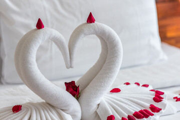 Honeymoon bed with white two towel swans and red rose on bed in Honey moon suit bedroom in hotel....