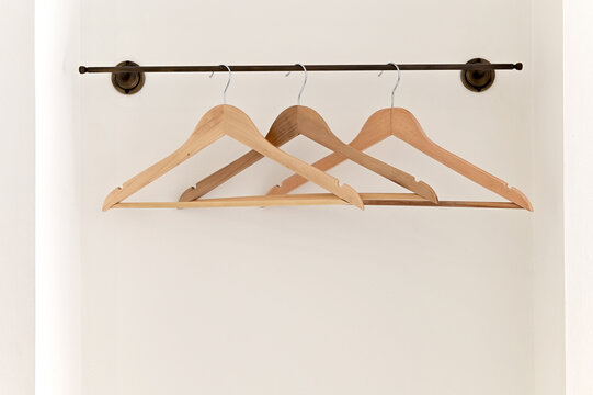 Three old wooden coat hangers on a white wall