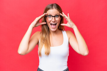 Young beautiful woman isolated on red background with surprise expression