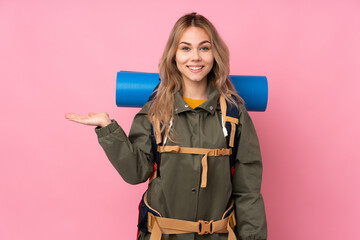 Teenager Russian mountaineer girl with a big backpack isolated on pink background holding copyspace imaginary on the palm to insert an ad