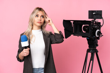 Reporter woman holding a microphone and reporting news over isolated pink background making the...