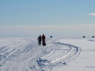 People walking on frozen Lake Simcoe to their ice fishing hut