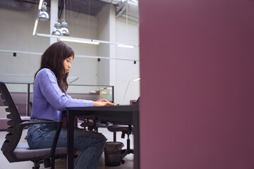 Concentrated female employee working on laptop indoors