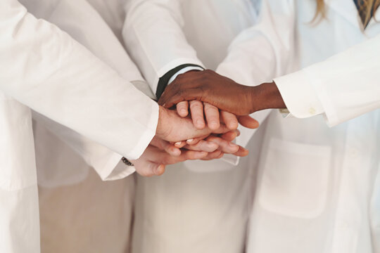 Doctors Teamwork in Action: Close-Up of United Hands in Lab Coats, Medical professional collaborating.