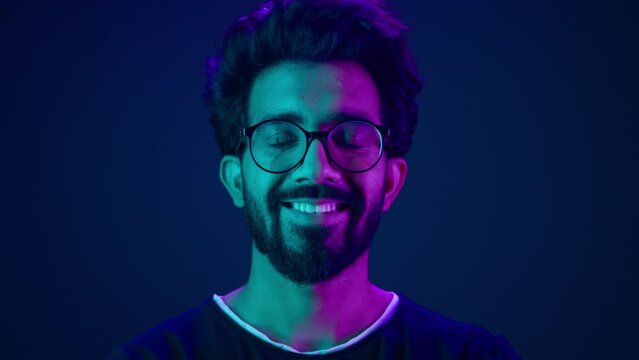 Portrait Indian man Muslim guy developer coding worker smile computer internet technology hacker Arabian male in glasses smiling neon blue ultraviolet studio background high-tech future cyberspace
