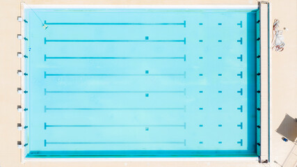 Aerial view of a large swimming pool with seven lanes and diving boards for diving competitions. The sports complex is empty and nobody is swimming.