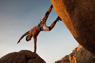 Athletic man in posed in a balance between boulders in the mountains. - 601720325