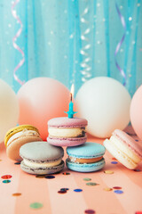 Macaroons and one candle on blue and pink background with air balloons, vertical celebration card