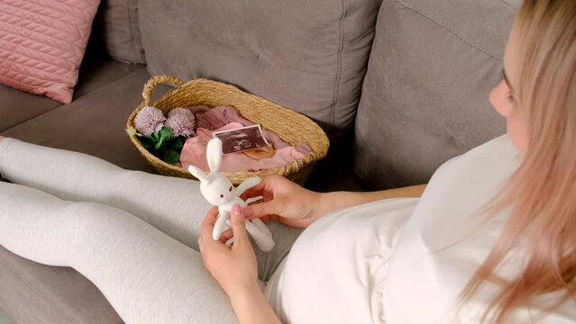 A pregnant woman looks at baby cloth and an ultrasound photo. Selective focus.