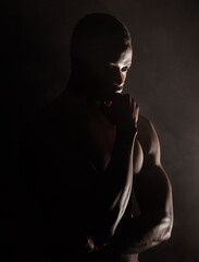 Black man, muscle silhouette and studio for thinking, anxiety and depression with art deco vision. Model, art aesthetic and depressed with strong body, alone or suffering with mental health in shadow