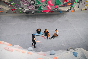 Looking Down On Multi-Cultural Group Of Friends Having Lesson From Coach On Climbing Wall © Southworks