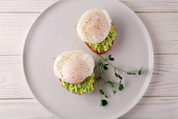 European breakfast. Toasted bread with avocado, poached egg and fruit juice on a white wooden table. healthy diet food