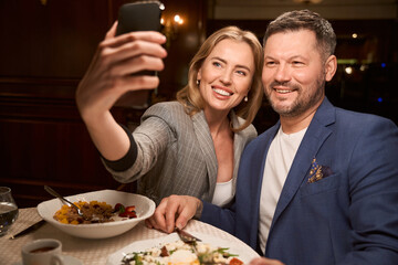Happy woman taking selfie with boyfriend from cafe