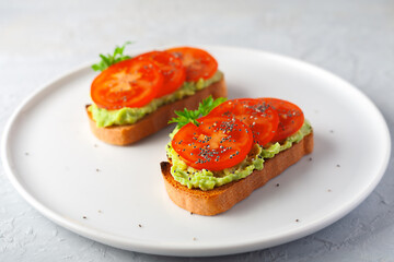Fototapeta na wymiar Vegan sandwich with avocado and tomatoes on a white dish