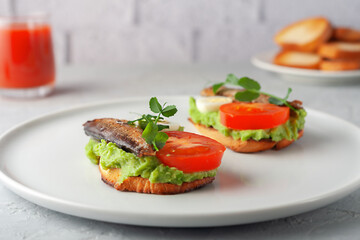 Sandwiches with sprats on toasted slices of bread. Sandwich with smoked sprat - fish, avocado and tomato.