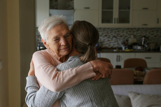 Geriatric social worker helping an elderly woman to get up. Senior sitter and old age lady hugging. Close up, copy space, background.