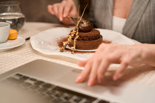 Woman working on laptop and eating sweet dessert