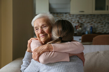 Grandmother and granddaughter hugging in the living room. Two adult women of different age. Family values concept. Close up, copy space, background.