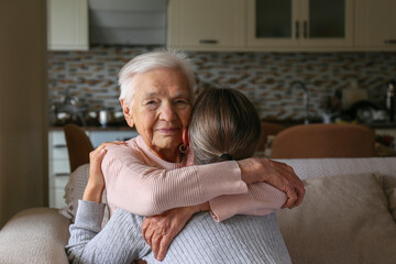 Grandmother and granddaughter hugging in the living room. Two adult women of different age. Family...