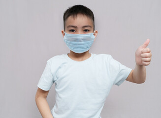 Young teen boy wearing medical mask and shows thumbs up Wearing a medical mask is good. corona virus concept. isolated on white background
